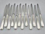 six silverplated knives and six knives on a white surface
