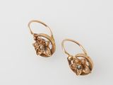 l'image d'une paire de boucles d'oreilles en or sur une surface blanche
