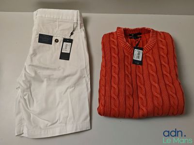 deux paires de pantalons blancs et un pull rouge posés sur une table