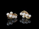 deux paires de boucles d'oreilles en perles et en or posées sur un fond noir