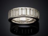 a white gold ring with baguets of diamonds on a black surface
