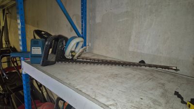 une photo d'une tronçonneuse posée sur une étagère dans un garage
