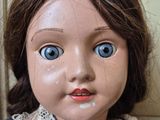 a close up of a doll with blue eyes and a lace collar