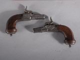 pair of antique silver plated pistols on display in a display case