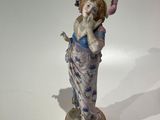 une figurine représentant une femme portant un chapeau et une robe