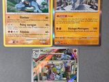Trois cartes Pokémon sont posées les unes à côté des autres sur une table.