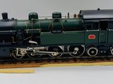 un train miniature posé sur une plate-forme en bois, sur une surface blanche