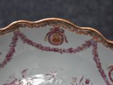someone is holding a plate with a pink and white design on it