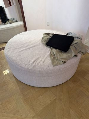 un pouf rond blanc sur lequel est posé un ordinateur portable