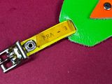 a green and orange luggage tag on a red surface