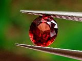 un gros plan d'un diamant rouge tenu par une pince