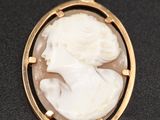 un pendentif camée doré et blanc représentant le visage d'une femme