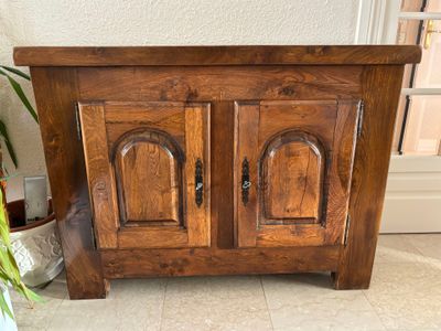 une armoire en bois à deux portes et une plante en pot dans un coin