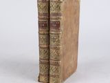 two old books sitting on top of each other on a white surface