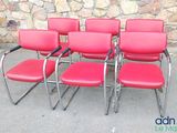 quatre chaises de bureau rouges placées devant un mur en pierre