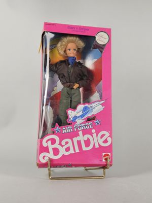 une poupée dans la boîte d'une poupée Barbie, tenant une batte de baseball