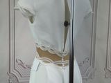 a white dress on a mannequin stand in front of a wall
