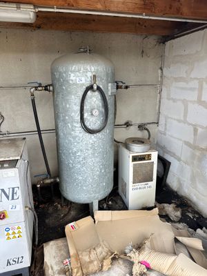 un chauffe-eau dans un coin de la pièce, à côté d'une pile de cartons