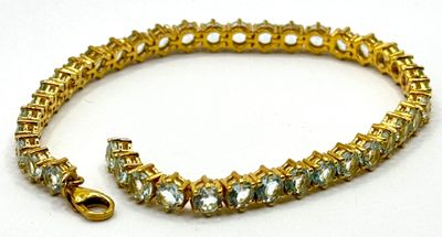 Gros plan sur un bracelet muni d'un fermoir doré, posé sur un fond blanc