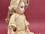 a doll that is sitting on the ground wearing a dress and hat