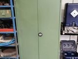 a green cabinet in the middle of a room filled with boxes