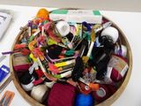 a wooden bowl filled with yarn, scissors and crochets