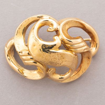 an image of a gold brooch with swirls on it