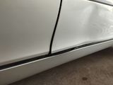 the side of a white car with a denting dent on it
