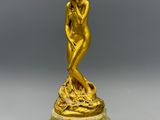 une statue en or représentant une femme assise sur un socle en marbre