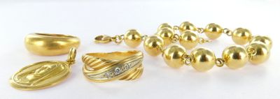 a gold bracelet, ring, and other jewelry on a white surface