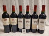 six bottles of wine are lined up in a row on a table