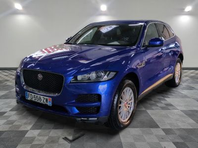 a blue jaguar suv parked in a showroom with a checkered floor