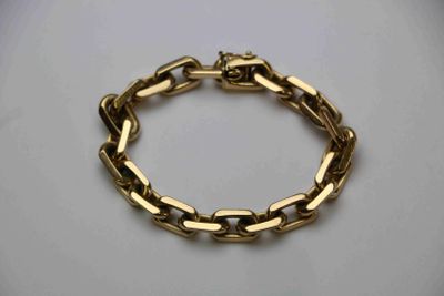 gros plan d'un bracelet en chaîne en or sur une surface blanche