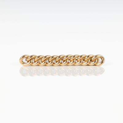 gros plan d'un bracelet en chaîne en or sur une surface blanche