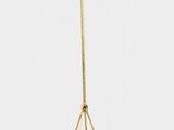 un lampadaire doré avec un pied en métal et un fond blanc
