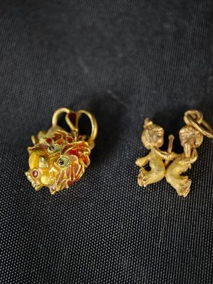 deux petits pendentifs en or sur un fond noir