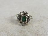 a close up of a ring with a green stone surrounded by white diamonds