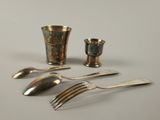 a silverware set on a table with a silver cup and spoon