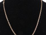 a gold chain necklace with an oval link on a mannequin neck