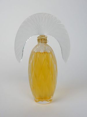 un flacon de parfum jaune surmonté d'un éventail blanc