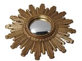 un miroir doré en forme de soleil rayonnant sur fond blanc