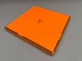 an orange book sitting on top of a table next to a gray table