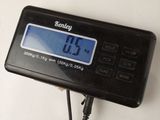 a digital clock that is on a table next to a pair of scissors