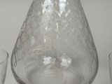 a clear glass bottle and glasses on a table