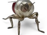 a metal sculpture of a bug with a pin in it ' s back