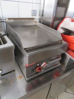 plan de travail en acier inoxydable dans une cuisine professionnelle équipée d'un four à plaque chauffante