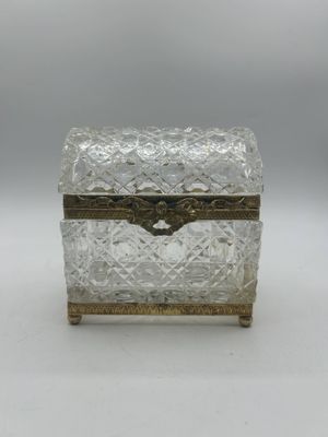 une boîte en argent et en verre munie d'une poignée, posée sur une surface blanche