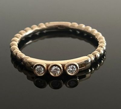 gros plan d'une bague en or et diamants sur une surface noire