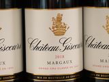 three bottles of red wine are lined up on a shelf