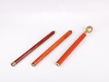 three red and gold colored pencils on a white surface